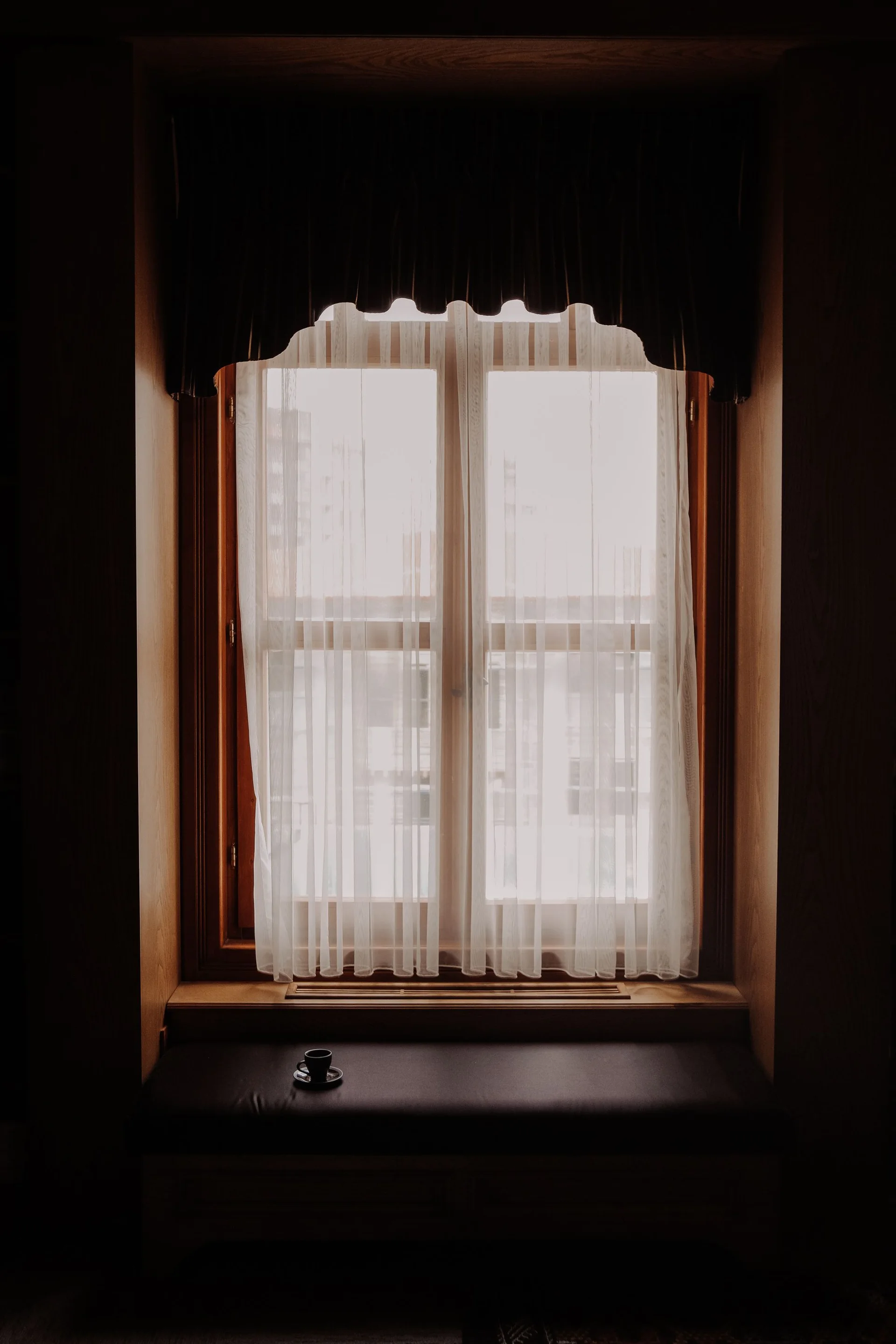 A window framed by outer curtains with a sheer inner layer
